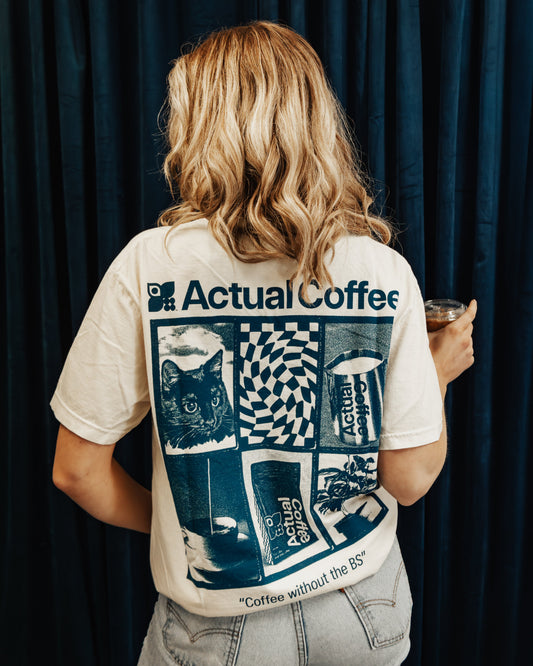 Person wearing a t-shirt with 'Actual Coffee' branding and graphics against a dark curtain.