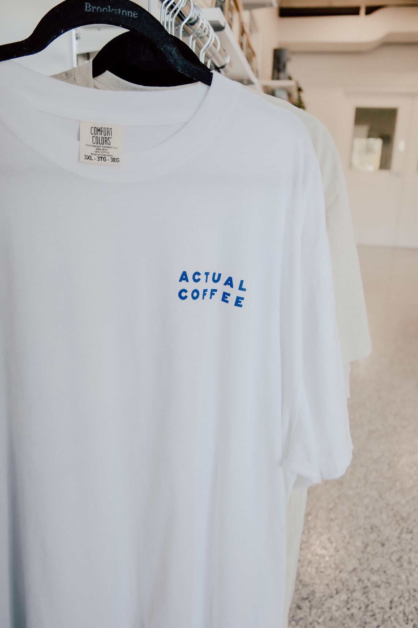 White t-shirt with 'Actual Coffee' text on a hanger