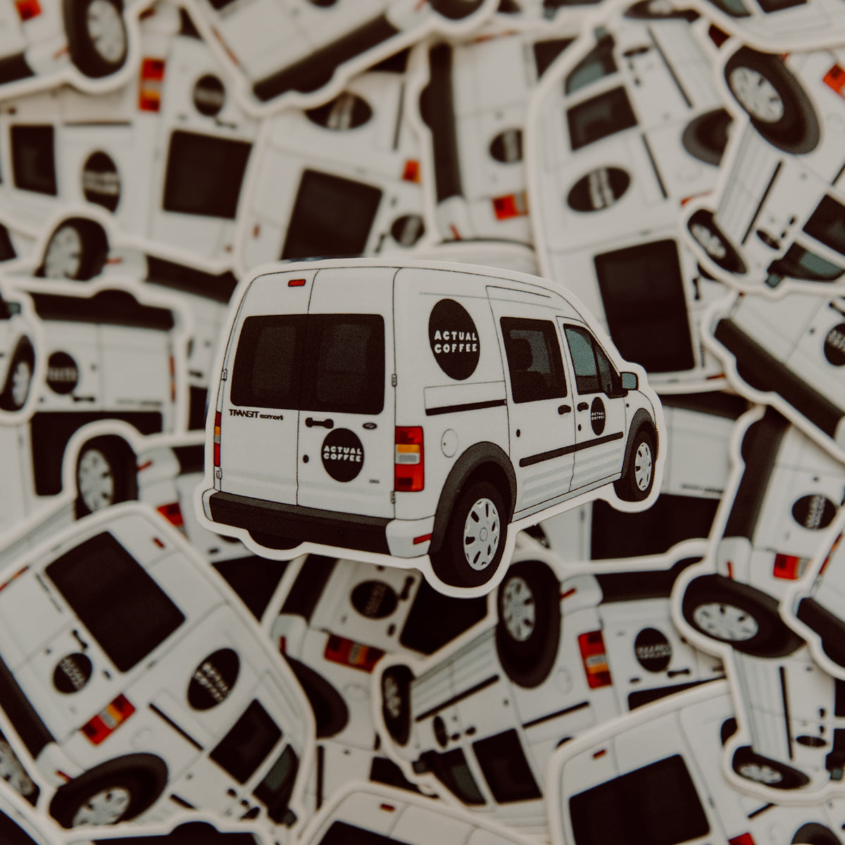Sticker of a white van with 'Actual Coffee' branding on a background of similar stickers.