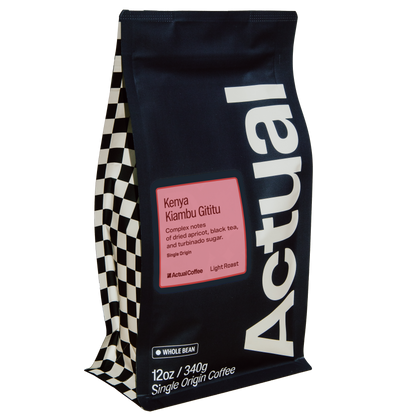 A 12 oz bag of Actual Coffee Kenya Kamtu Glitu single origin coffee. The bag is dark navy blue with a large white vertical 'Actual' logo, a pink label in the center, and a black and white checkered pattern on the left side.