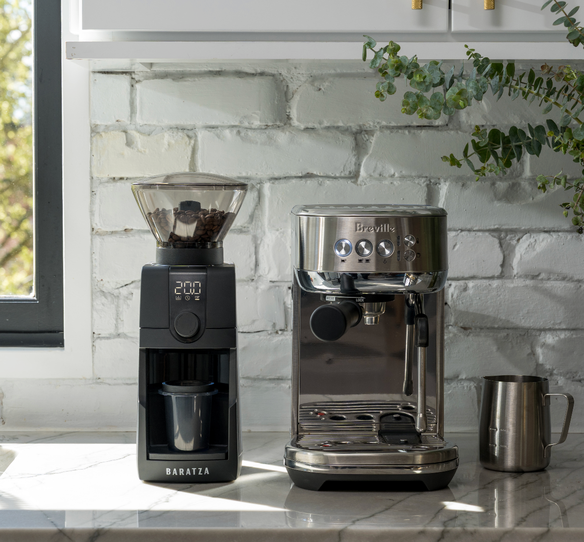 Baratza ESP Pro coffee grinder and espresso machine on a kitchen counter with a white brick wall background.